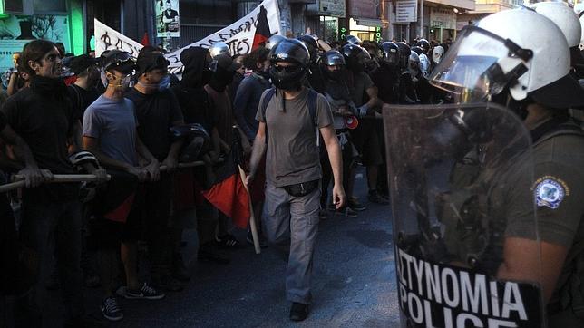 Manifestantes permanecen frente a policías antimotines durante una marcha contra el nazismo en Atenas