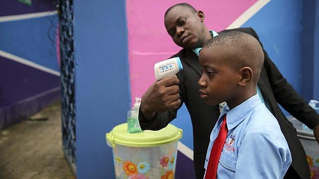 Un trabajador toma la temperatura a un estudiante usando un termómetro láser en una escuela