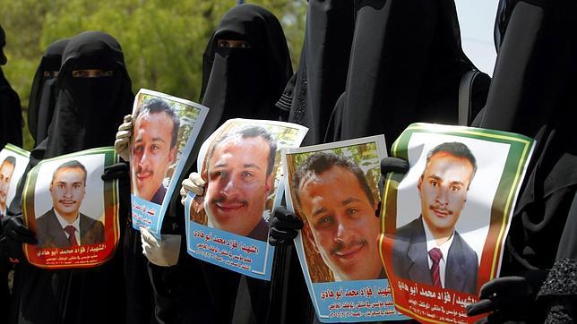 Mujeres yemeníes sostienen imágenes de las víctimas del asedio aéreo