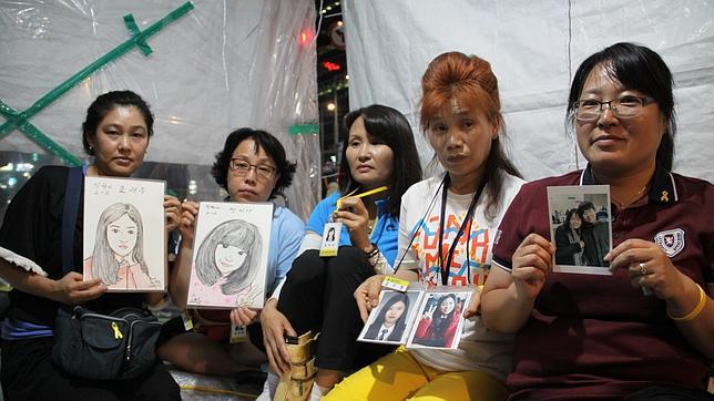 Las madres de algunas de las víctimas del naufragio del Sewol muestran sus fotos y retratos