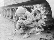 Un niño checheno juega delante de un carro del Ejército ruso ABC