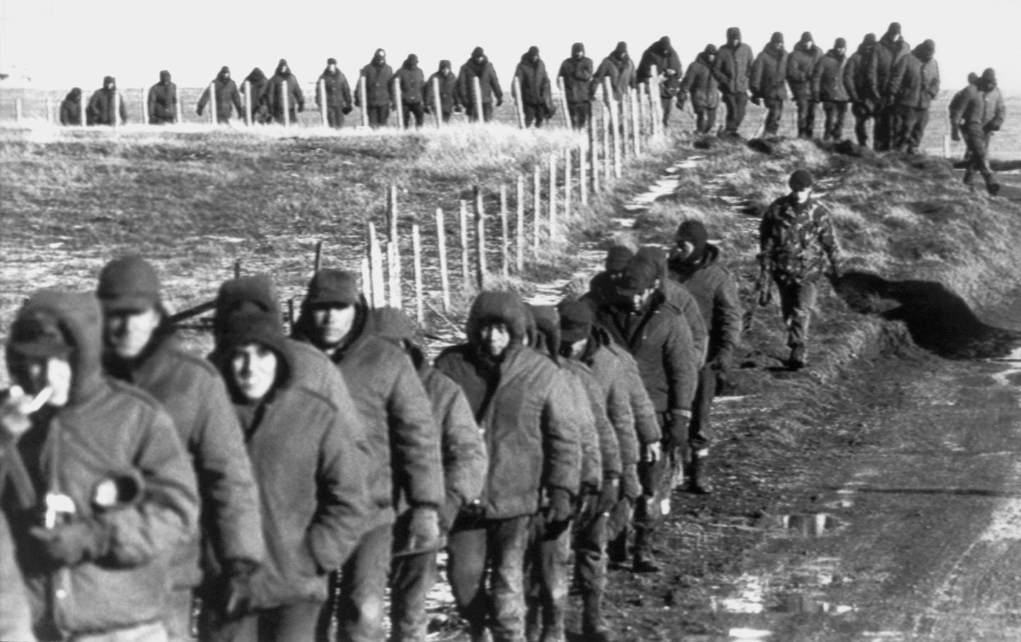 Los soldados argentinos (en primer plano) son escoltados por soldados británicos después de rendirse el 2 de junio de 1982 cerca de Goose Green, durante la Guerra de las Malvinas 