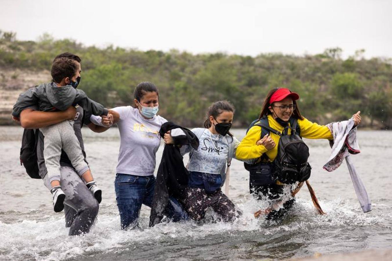 Un grupo de inmigrantes intenta cruzar de la mano las aguas del Río Bravo
