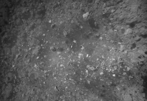 Imagen de la superficie del asteroide Ryugu justo después del aterrizaje. Los escombros salen disparados hacia arriba