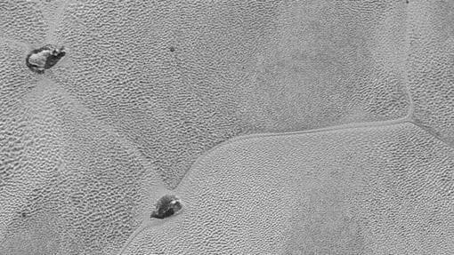 Esta imagen detallada de los glaciares en el Planputia Sputnik de Plutón, de aproximadamente 50 millas de ancho, muestra miles de pozos en su superficie de hielo de nitrógeno, así como patrones de circulación más grandes. Los científicos sospechan que las «islas» son icebergs flotantes de hielo de agua, o tal vez las puntas de las montañas de hielo