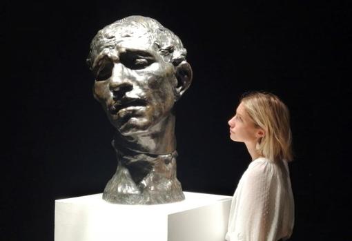 Una mujer pasa ante la escultura «L'un des Bourgeois de Calais: Tête colossale de Pierre de Wissant» del artista francés Auguste Rodin