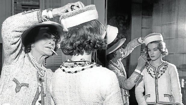 Coco Chanel, fotografiada mientras le prueba un traje a Romy Schneider