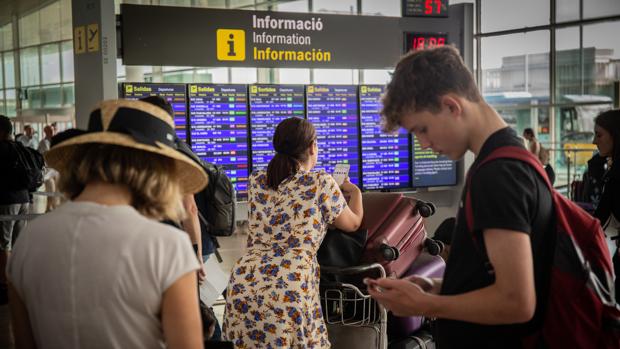 Diferentes viajeros esperan frente al panel de información de los vuelos de Salida del Aeropuerto Josep Tarradellas Barcelona-El Prat, durante la huelga del personal de tierra de Iberia en Barcelona