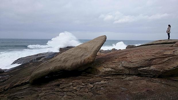 Una mujer contempla el Atlántico junto a la Pedra de Abalar, junto al santuario de la Virxe da Barca en Muxía