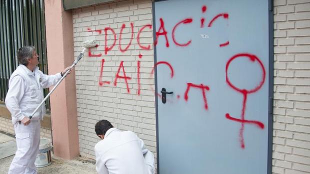 Los operarios limpian las paredes exteriores del templo con las pintadas