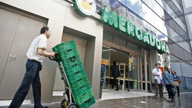 Imagen de un empleado de Mercadona frente a un supermercado de Mercadona en el centro de Valencia