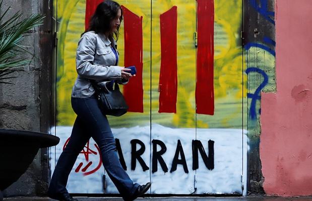 Una mujer pasa junto a una puerta pintada por Arran con una estelada