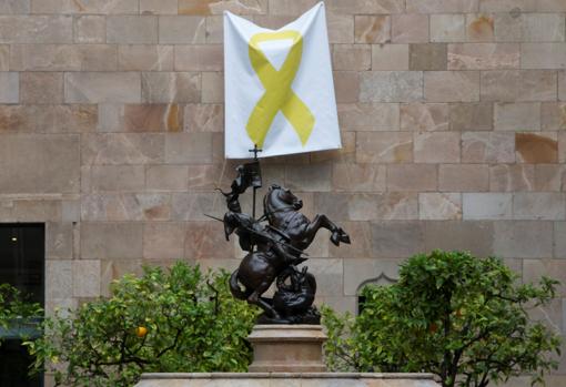Una pancarta con un lazo amarillo cuelga de una de las paredes del Pati dels Tarongers