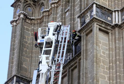 Un bombero trabaja desde la autoescala en una cornisa situada por debajo del campanario