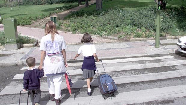 Dos alumnos vestidos con uniforme escolar circulan por un paso de cebra