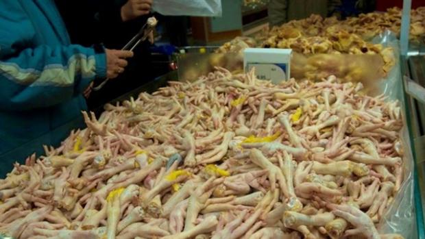 Imagen de un trabajador con un recipiente lleno de patas de pollo