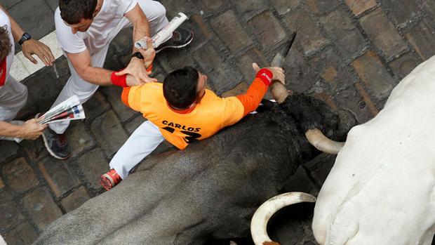 «Carlos 13» en el momento de agarrarse a un cuerno de un toro de José Escolar en el encierro del 9 de julio