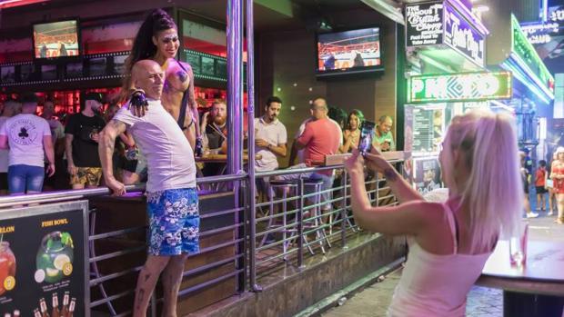 Un jubilado se fotografía junto a una gogó en topless en la calle Mallorca de Benidorm