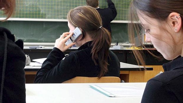 Alumna utilizando el móvil en una clase