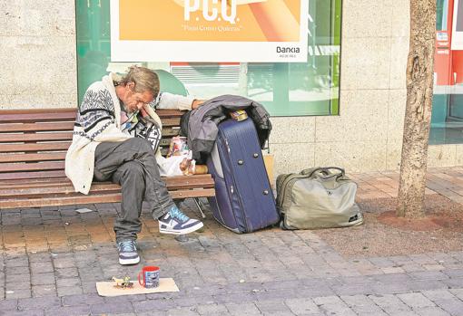 Un hombre sin hogar duerme en un banco de la avenida de la Libertad, junto a sus enseres