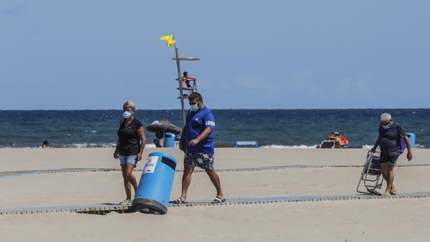 Varias personas con mascarilla en la playa del Cabanyal de Valencia