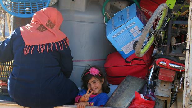 Una niña siria sonríe desde un camión en un puesto de control en Líbano