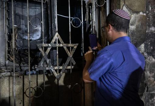 Un hombre israelí mira una sinagoga incendiada en los enfrentamientos en Lod