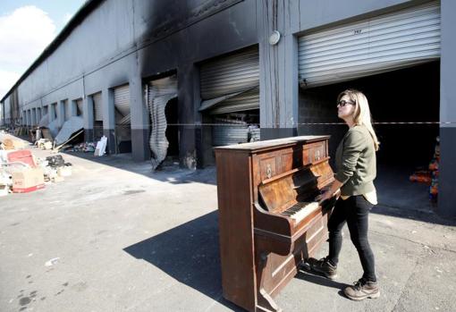 Jenny Bowes toca el piano ante unos trasteros saqueados en Waterfall