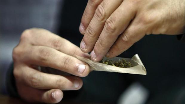 Un hombre liando un cigarrillo de marihuana