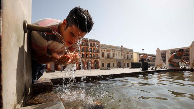 Un joven se refresca en la fuente del patio de los naranjos de la mezquita catedral de Córdoba
