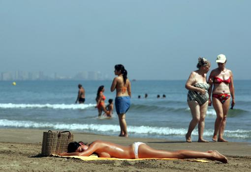Una joven toma el sol en la playa de las Arenas de Valencia
