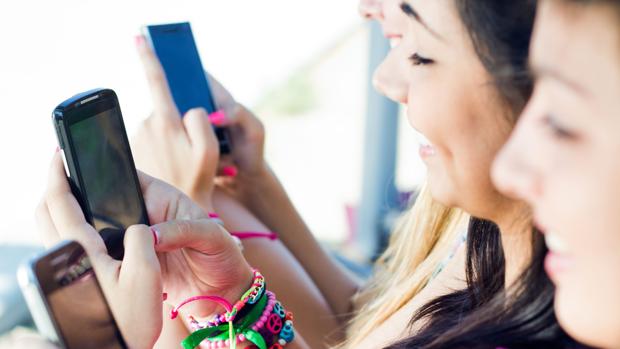 Unos jóvenes utilizan sus terminales móviles para comunicarse a través de internet